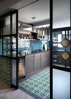 an open door leading to a kitchen with blue and green tiles on the wall,