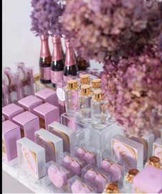 a table topped with lots of pink and gold boxes next to purple hydranges