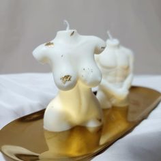 two white candles sitting on top of a gold spoon