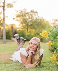 a woman laying in the grass with her legs crossed and looking up at the camera