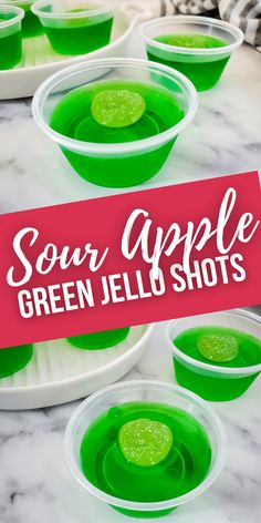 some green jello shots in plastic bowls on a marble table with the words sour apple green jello shots