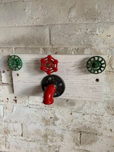 three red and green knobs on a white brick wall