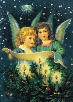 two angels sitting next to each other on top of a christmas tree with lit candles