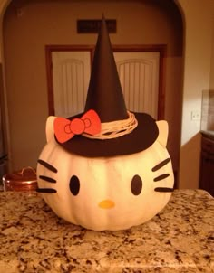 a hello kitty pumpkin sitting on top of a kitchen counter with a black cat hat