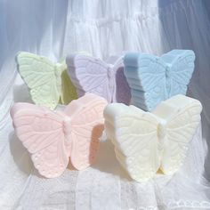 four butterfly shaped soaps sitting next to each other on a white cloth covered table