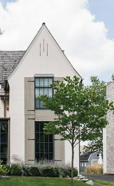 a large white house sitting on top of a lush green field next to a tree