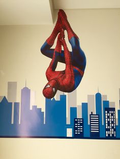 a spider man mural on the side of a wall in a room with city skylines