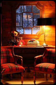 two red chairs sitting next to each other in front of a table with a book on it