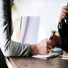 two people sitting at a table writing on paper