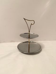 two tiered serving tray with metal handles on white tablecloths and plain background