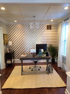 an office with a desk, chair and rug on the floor in front of a window