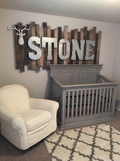 a baby's room with a rocking chair, crib and stone sign on the wall