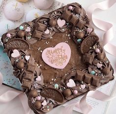 a heart shaped chocolate cake sitting on top of a table covered in pink and brown decorations