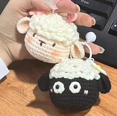 a hand holding a crocheted sheep ornament next to a computer keyboard