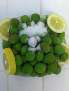 lemons, limes and sugar are arranged in the shape of a bowl on a tile floor