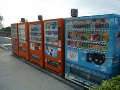 a row of vending machines sitting next to each other on the side of a road