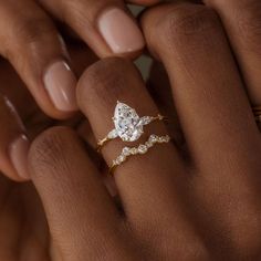 a woman's hand holding a diamond ring with two diamonds on the middle finger