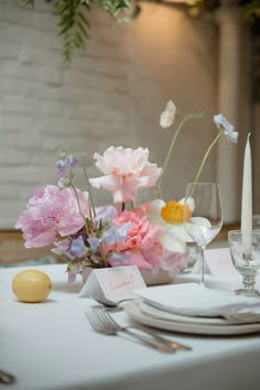 the table is set with flowers, candles and place cards for guests to sit at