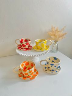 four colorful cups and saucers on a white table