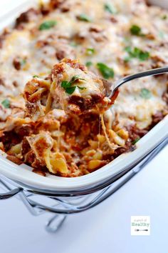 a casserole dish with meat and cheese being lifted from the casserole