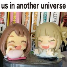 two anime figurines sitting next to each other on top of a book shelf