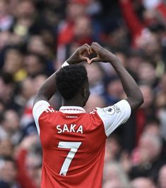 a soccer player with his hands in the shape of a heart on his head at a game