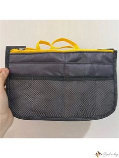 a person holding up a gray and yellow purse