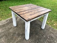 a white and brown table sitting on top of a cement ground next to green grass