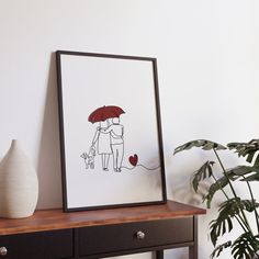 a drawing of two people under an umbrella on a table next to a potted plant