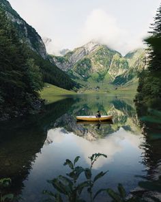 a person in a canoe on a lake surrounded by mountains