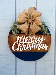 a wooden sign that says merry christmas hanging on the side of a building with a bow