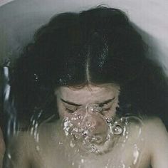 a woman is taking a bath in a tub with water coming out of her mouth