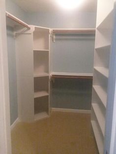 an empty walk in closet with white shelves