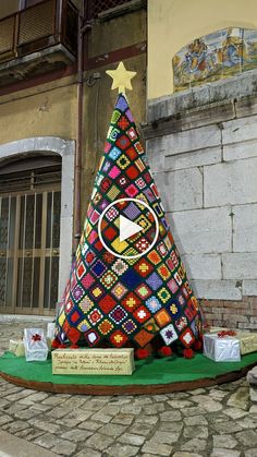 a colorful christmas tree on display in front of a building