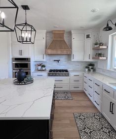 a large kitchen with white cabinets and marble counter tops, an island in the middle