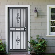 a black and white door is in front of a house with plants on the side