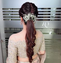 the back of a woman's head with long hair and flowers in her hair