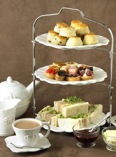 three tiered trays filled with different types of pastries and teacups