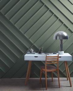 a desk with a chair and lamp on it in front of a wallpapered background