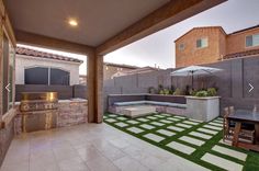 an outdoor kitchen and grill area with grass on the floor