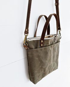 "This slim and versatile waxed canvas crossbody hand bag is ready to carry what you need for your day. This purse features deep and spacious exterior and interior pockets perfect for fitting your phone and keys. The two inch depth of the bag can fit larger items such as a water bottle, iPad, glasses case, etc while still remaining slim and not adding extra bulk.  Waxed canvas is cotton canvas that is permeated with wax making it water resistant and durable. Over time, waxed canvas will achieve its' signature marbling which resembles distressed leather. This textured look is what we love about waxed canvas!  My waxed canvas, interior fabrics, hardware, and leather are all sourced from U.S. companies. I tool and handcraft each leather strap using the highest quality leather from a tannery th Waxed Canvas Bag For Everyday Use, Everyday Waxed Canvas Bag With Zipper Pocket, Waxed Finish Crossbody Canvas Bag For Daily Use, Daily Use Waxed Canvas Crossbody Bag, Waxed Canvas Tote Bag, Dopp Bag, Work Tote, Toiletry Bag Travel, Vintage Canvas