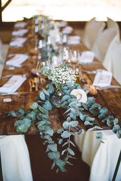 the table is set with eucalyptus and baby's breath flowers