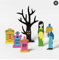 paper cut out of halloween characters and tombstones in front of a tree with jack - o'- lanterns on it