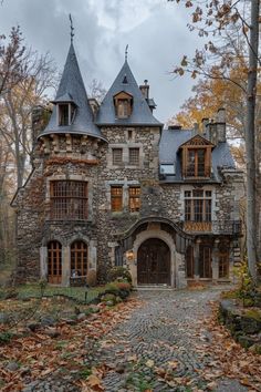 an old castle like building in the middle of leaves on the ground and trees around it