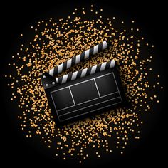 a movie clapper surrounded by gold flakes and confetti on a black background