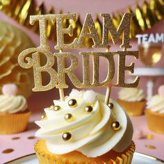 a cupcake on a plate with the word team bride spelled out in gold letters