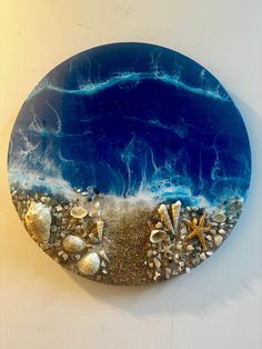 a blue plate with shells and starfishs on it is hanging on the wall