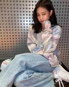 a young woman sitting on top of a wooden floor next to a metal panel wall