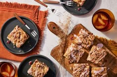 some desserts are sitting on black plates and orange napkins next to each other