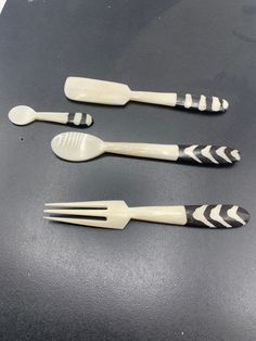 three plastic utensils sitting on top of a black table next to each other